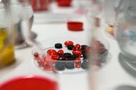 pexels-photo-7230326-7230326 Close-up view of red and black pills on a lab table with blurred background.